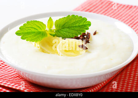 Ciotola di liscio budino di latte con fette di banana e cioccolato grattugiato Foto Stock