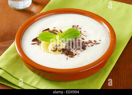 Ciotola di liscio budino di latte con fette di banana e cioccolato grattugiato Foto Stock