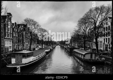 Inverno a Amsterdam, paesaggio di case galleggianti lungo il canale su una nebbia e piovosa giornata invernale. Foto Stock