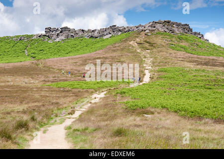 Il percorso che conduce fino a Higger Tor con molte persone su e intorno alle rocce. Il Peak District, Derbyshire. Foto Stock