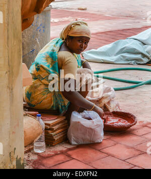 THANJAVOUR, India - 14 febbraio: non identificato una donna indiana in costumi nazionali suscita il colorante rosso nel recipiente. India, Tamil Nad Foto Stock