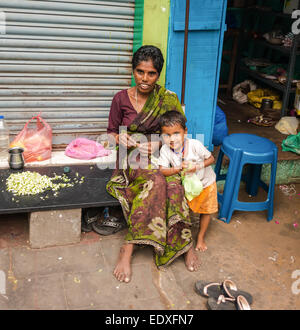 THANJAVOUR, India - 14 febbraio: una donna non identificato con il bambino nel tradizionale abbigliamento indiano sono seduti. La donna tesse una garla Foto Stock