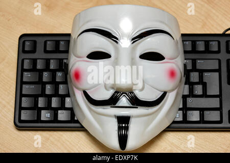 Anonimo maschera hacker giacente sulla tastiera di un computer Foto Stock