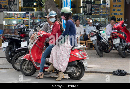 Due donne vietnamita su scooter con maschera a proteggerli dall'inquinamento la città di Ho Chi Minh Saigon Vietnam Foto Stock