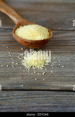 Couscous crudo in un cucchiaio di legno, alimentari close up Foto Stock