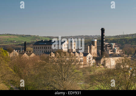 Alta vista sulle cime degli alberi del Mulino Damart edifici industriali e le torreggianti, nero fabbrica tessile camino - Bingley, West Yorkshire, Inghilterra, Regno Unito. Foto Stock