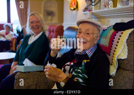 La casa di cura in Bungay, Suffolk England Regno Unito. Paziente con il cappello e la famiglia e gli amici donna ridere sono modello rilasciato ma non il personale infermieristico o donna in background sulla sinistra in questa immagine. Foto Stock