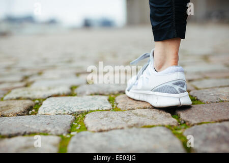 Gamba del pareggiatore femmina camminando sul marciapiede. La messa a fuoco di scarpe. Donna piedi sul marciapiede. Foto Stock