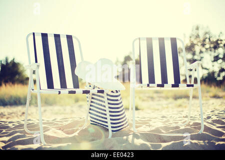 Spiaggia di due saloni con borsa da spiaggia e cappello bianco Foto Stock