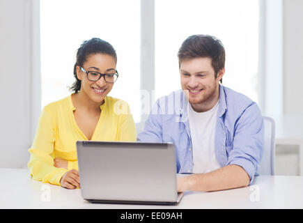 Due persone sorridenti con il computer portatile in ufficio Foto Stock