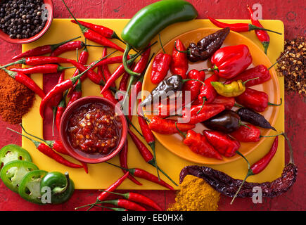 Un gruppo di luminoso colorato peperoncini su uno sfondo di colore rosso. Foto Stock