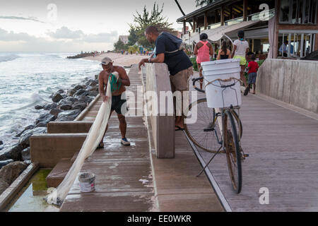 Fisherman pesca al largo di Hastings rocce sulla costa sud di Barbados - solo uso editoriale Foto Stock