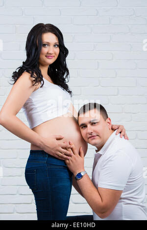 Futuro papà ascolta teneramente incinta pancia Foto Stock