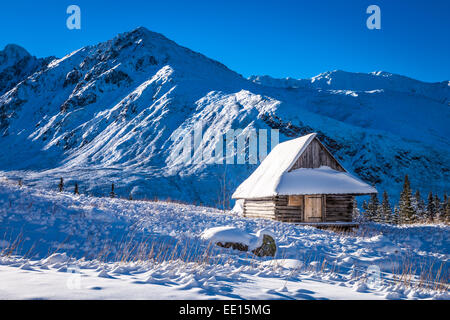 Piccola casa coperte di neve in montagna Foto Stock