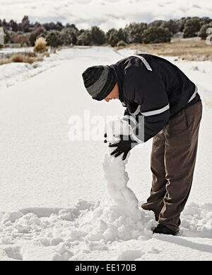I giovani adulti in tempesta di neve rendendo pupazzo di neve e sorridente Foto Stock