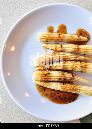 Baby Insalata di mais wite salsa di sesamo sul piatto bianco Foto Stock