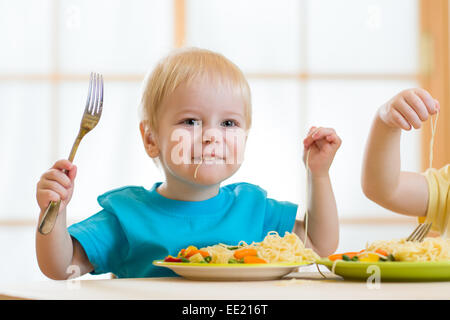 Kid mangiare spaghetti con verdure in vivaio Foto Stock