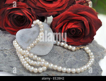 Collana di perle di perla sul cuore di pietra con rose rosse Foto Stock