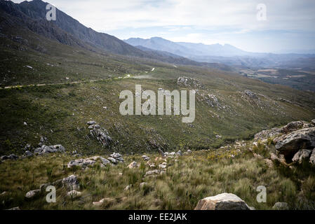 La strada arrivando fino al lato sud della Swartberg Pass sulla R328 di strada nella Western Cape, Sud Africa. La polvere da un'auto. Foto Stock