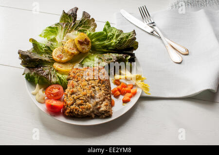 Filetti di merluzzo impanato e cotto al forno con patate e insalata per guarnire Foto Stock