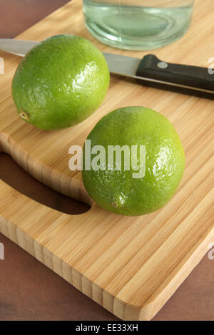 Verde lime persiano su di un tagliere in attesa di essere affettato per bevande o per la cottura Foto Stock