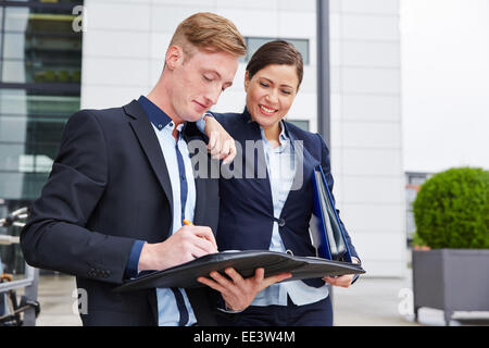 Due lieti consulenti contratti di lettura sul muoversi in città Foto Stock