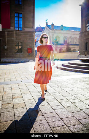 Senior donna a piedi lungo piazza, Monaco di Baviera, Germania Foto Stock