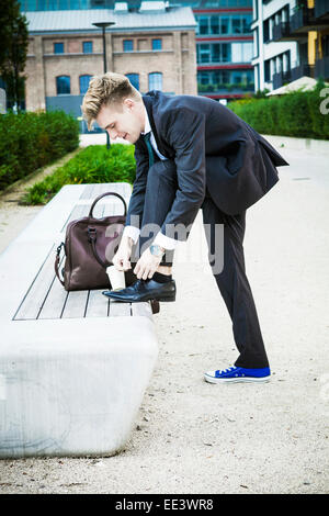 Giovane imprenditore mettendo sulle scarpe, Monaco di Baviera, Germania Foto Stock