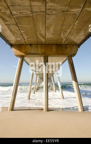 Bel punto di fuga sotto un molo su Hermosa Beach a Los Angeles California con onde durante il giorno Foto Stock