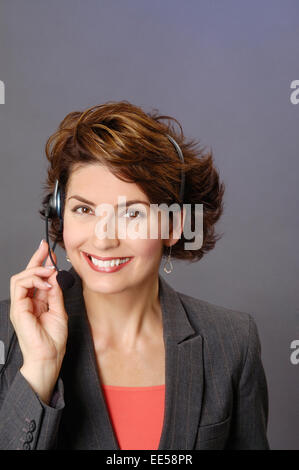 Attraente brunette adult business donna, indossa una cuffia telefonica e tuta giacca. Foto Stock