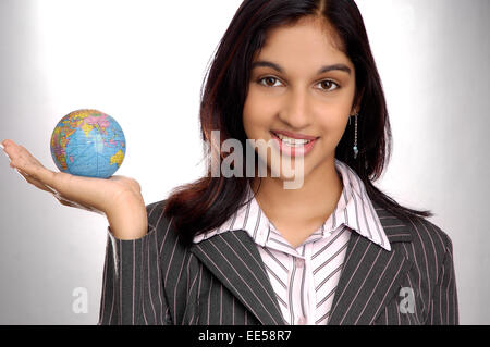 Indian business donna tenendo un piccolo globo in mano Foto Stock