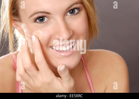 Questo stock mostra fotografica di una giovane donna di applicare foundation make-up o correttore. Foto Stock