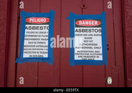 Amianto cartelli di avvertimento in inglese ed in spagnolo in cantiere, San Diego, California USA Foto Stock