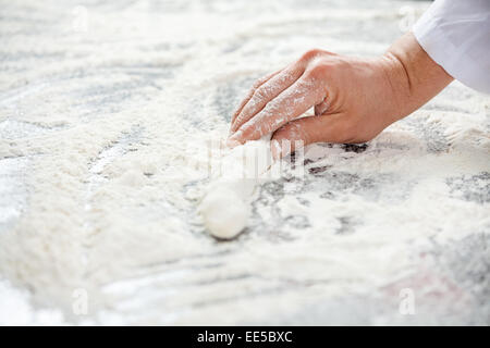 Femmina di mano dello chef azienda impasto al contatore disordinati Foto Stock