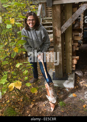 Donna di legna da ardere di trinciatura con ax, Lago dei boschi, Ontario, Canada Foto Stock