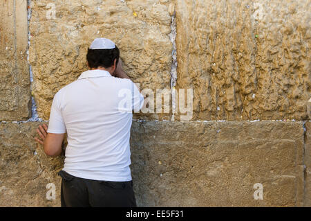 Un uomo ebraico è pregare contro il muro occidentale nella città vecchia di Gerusalemme Foto Stock