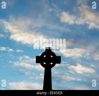 Stone celtic cross contro il cielo blu nelle prime ore del mattino. Silhouette Foto Stock