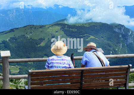 Coppia in pensione riposo su una panchina in montagna italiana, il Lago di Garda Foto Stock