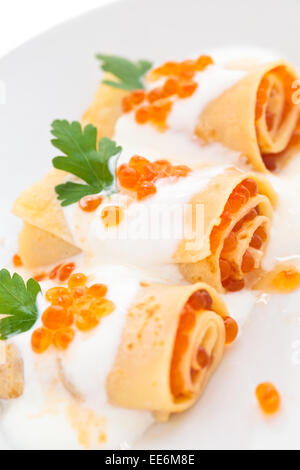 Frittelle con caviale rosso e salsa bianca sulla piastra bianca. Foto Stock