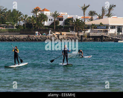L uomo e la donna in piedi up paddling le tavole da surf e windsurf in Caleta de Fuste bay Fuerteventura Isole Canarie Foto Stock