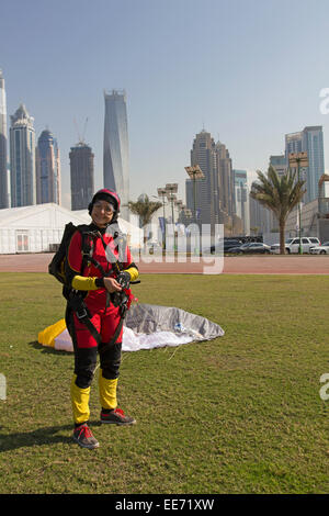 Skydiving ragazza sbarcati salvare sul prato di fronte al Dubai sky raschiatori. In tal modo lei è sorridente come una Lady Bird. Foto Stock
