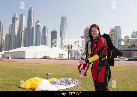 Questa ragazza paracadutista è sorridente dopo un salvataggio di atterraggio con il paracadute sull'erba verde area. Lei salta da 13'000ft altitudine sopra Dubai Foto Stock