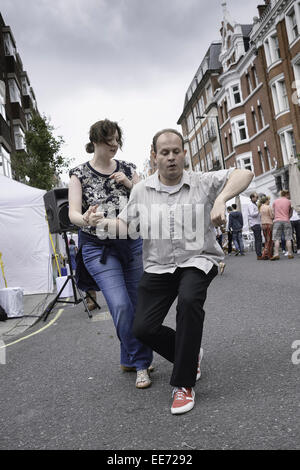 Un entusiasta ballo di coppia un Samba su strada a London Street Fayre. Foto Stock