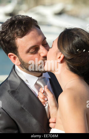 Coppia sposata nel giorno del loro matrimonio. Sposa tira la cravatta dello sposo mentre baciare lui. Foto Stock