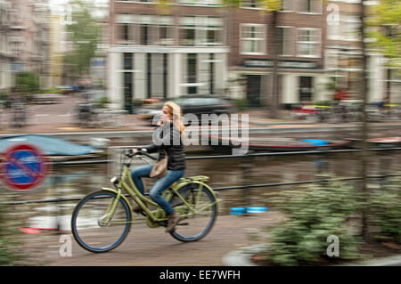 Equitazione Amsterdammer attraverso una strada di città Foto Stock