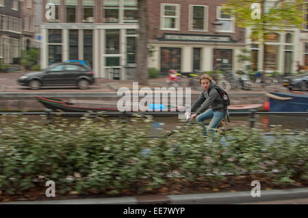 Equitazione Amsterdammer attraverso una strada di città Foto Stock