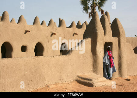 Un imam sorge all'entrata di un tradizionale di mattoni di fango moschea in un villaggio vicino a Djenne, Mali Foto Stock