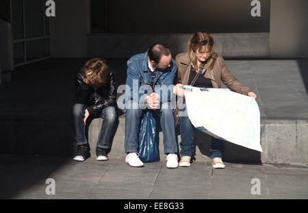 Famiglia di turisti in cerca della mappa, seduto sul passo, fuori il museo MACBA nel quartiere Raval di Barcellona. Foto Stock