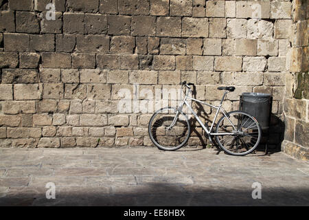 Bike in appoggio contro la parete in Plaça del Rei, quartiere Gotico di Barcellona e luminosa giornata di sole. Foto Stock