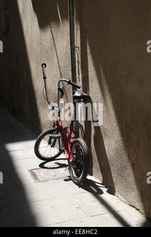 Rosso del bambino bici BMX contro la parete in strada di El Raval e luminosa giornata di sole. Foto Stock